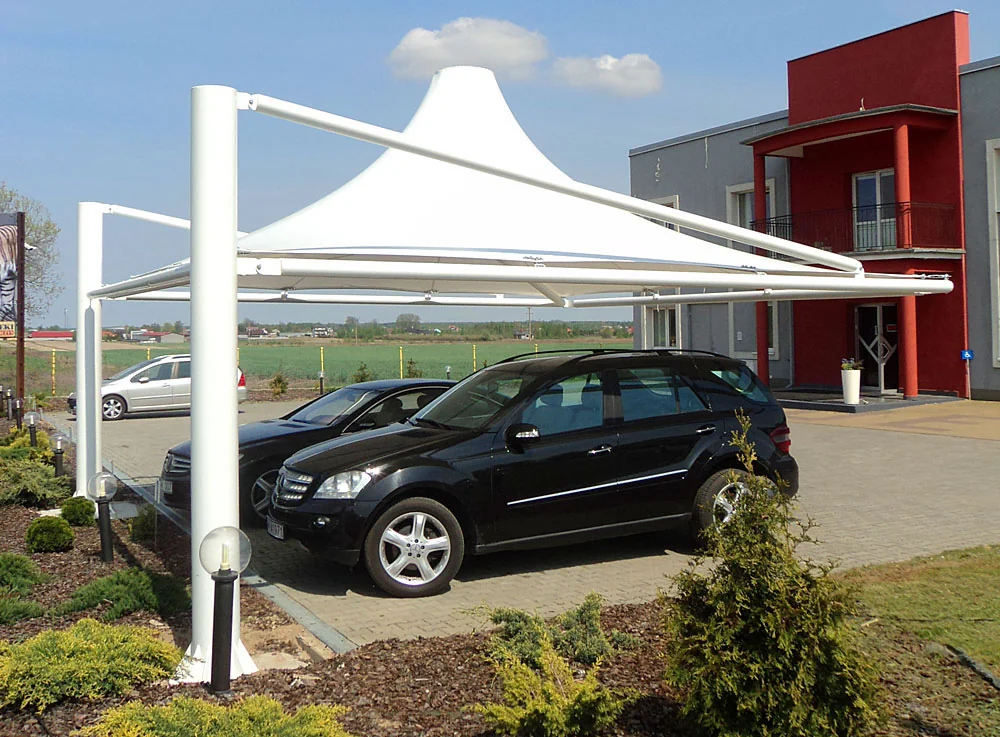 Membranowa wiata parkingowa (carport) na masztach nad samochodami przed budynkiem