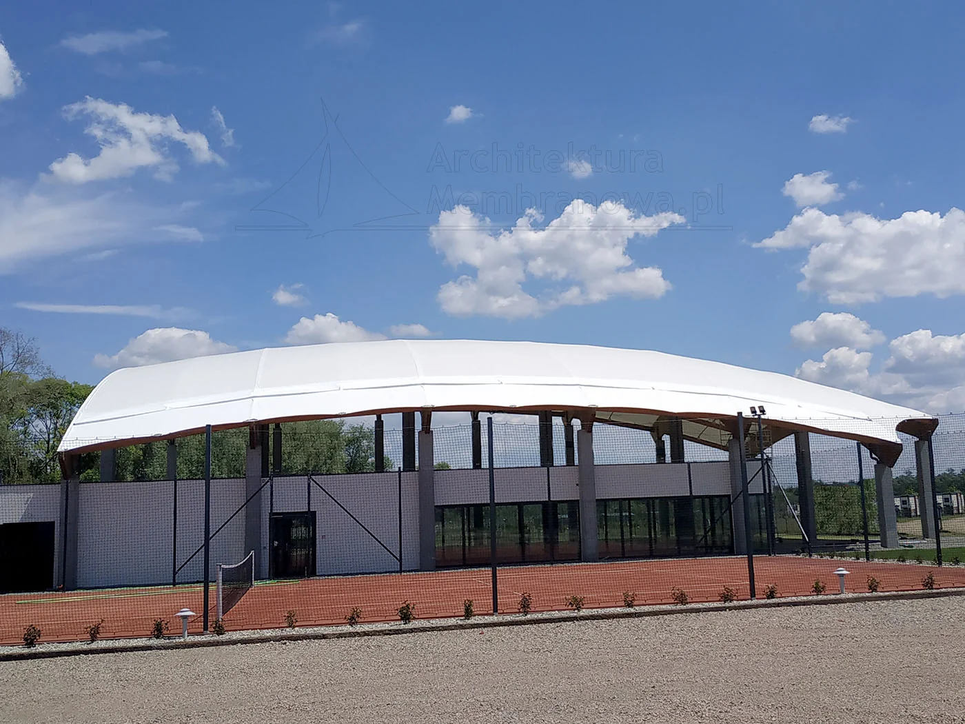 Łukowe membranowe zadaszenie hali sportowej na drewniano-stalowej konstrukcji przy korcie tenisowym