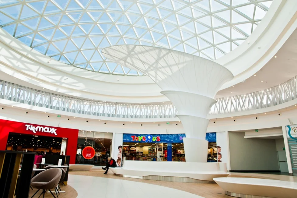 Atrium galerii handlowej ze szklaną kopułą i membranowym lejem rozpiętym na centralnym słupie