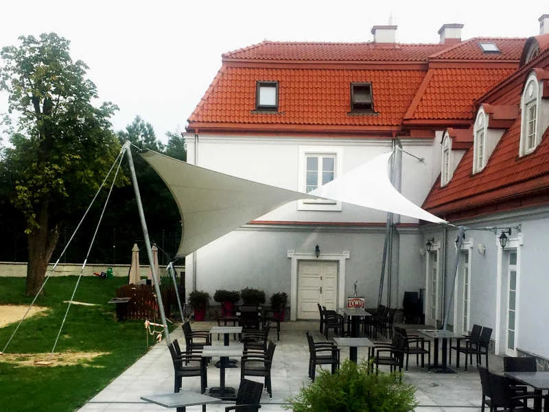 Membranowe żagle nad tarasem gastronomicznym przy zabytkowym pałacu