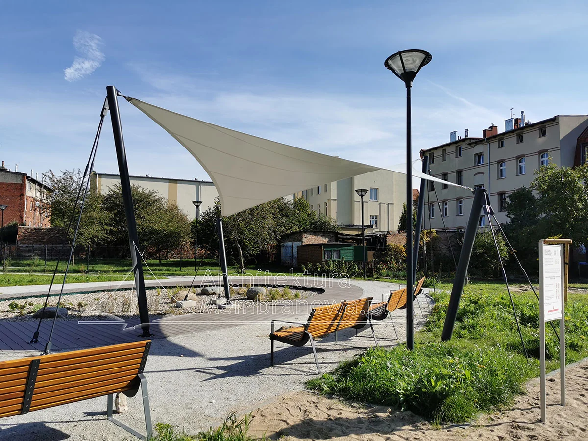 Napinany żagiel membranowy zacieniający plac zabaw z ławkami na masztach stalowych