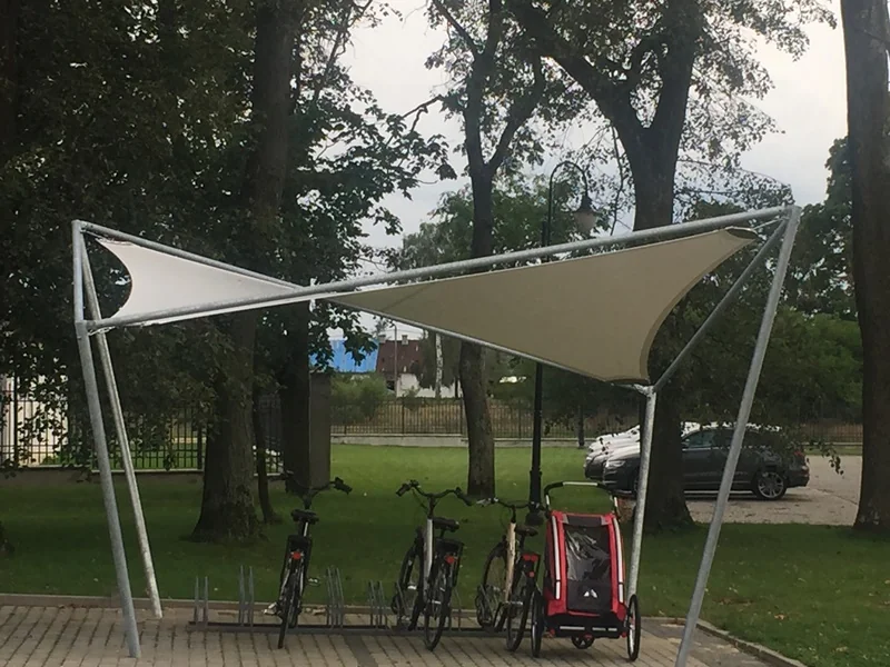 Zadaszenie membranowe (beżowe żagle na stalowej ramie) nad stojakiem na rowery