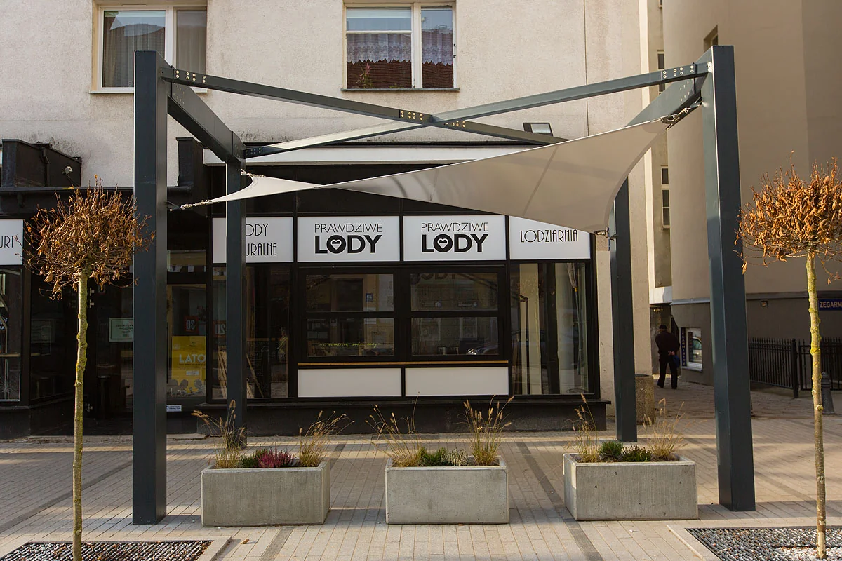 Membranowe zadaszenie lodziarni na stalowej konstrukcji nad witryną lokalu